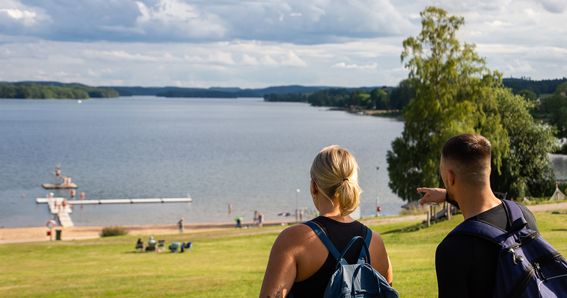 Två personer blickar ut över Åsundabadet i Rimforsa.