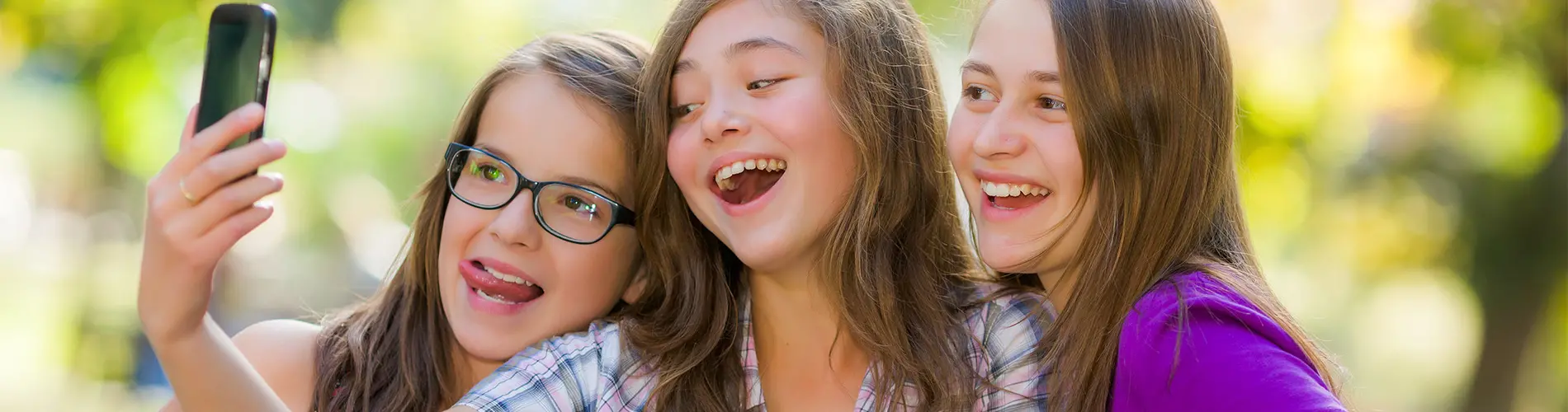 Bild på tre glada tjejer som tittar på en mobil
