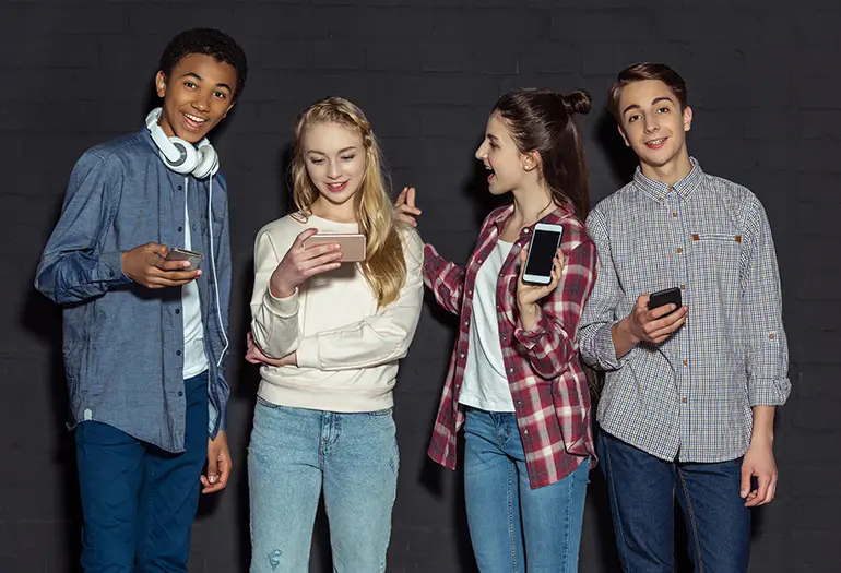 bild av fyra ungdomar med telefon