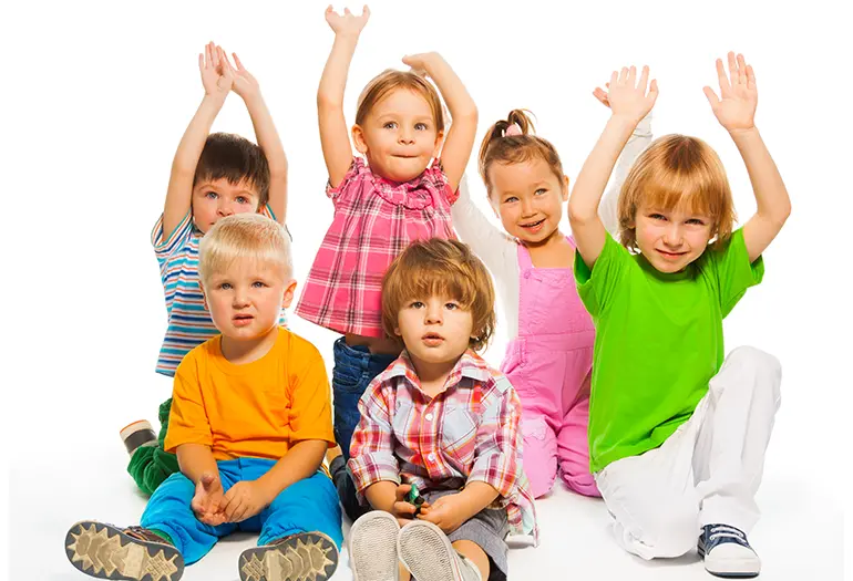 Ett antal barn som ler och sträcker upp sina händer i luften
