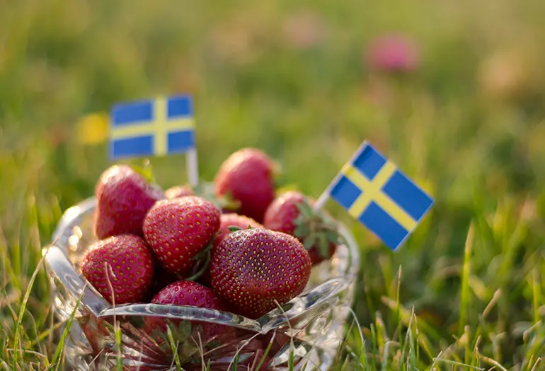 En skål jordubbar med små svenska flaggor nedstuckna som prydnad